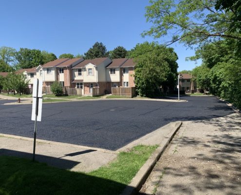 Image depicts a parking lot with new asphalt sealing.