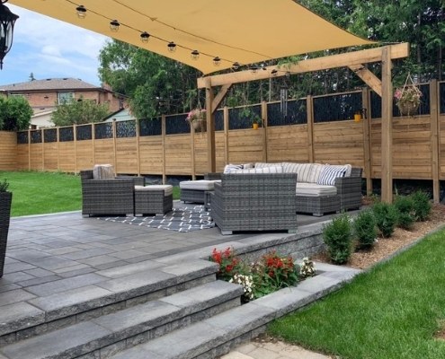 Image depicts a modern backyard interlocking patio with patio furniture that was done by Action Home Services.
