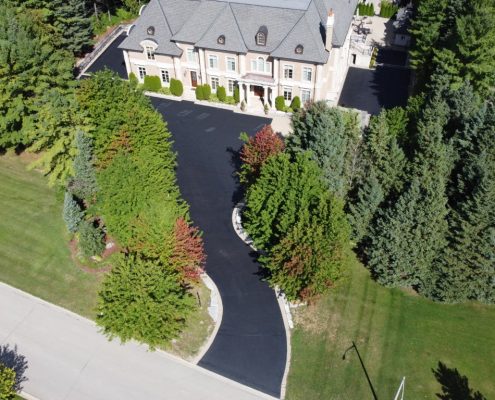 Image depicts a large asphalt driveway that has been sealed.