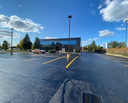 Image depicts a commercial parking lot with asphalt that has been sealed.