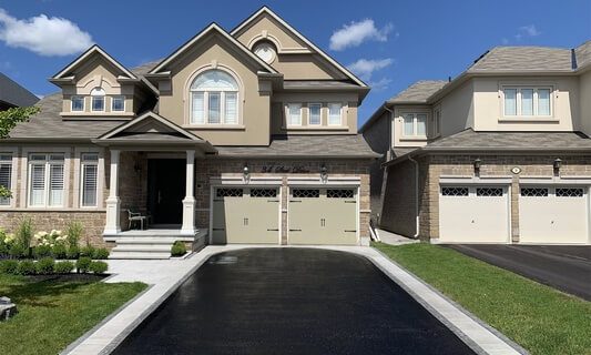 Image depicts a residential asphalt driveway that has been sealed by AHS.