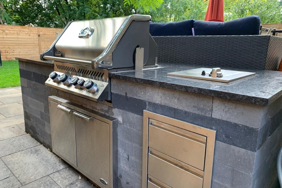 Image depicts a backyard outdoor kitchen with a barbeque.
