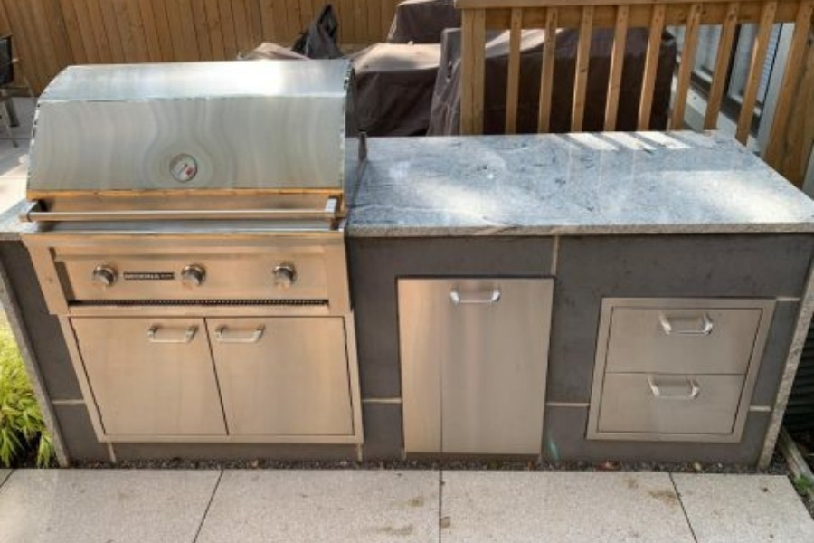 Image depicts a backyard outdoor kitchen with a barbeque.