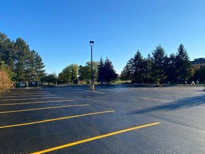 Image depicts a parking lot with sealed asphalt and newly painted parking lines.
