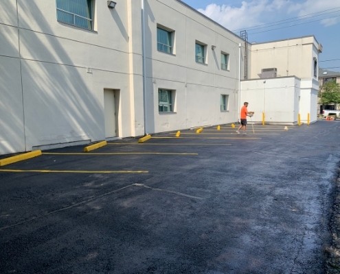 Image depicts a parking lot with asphalt that has been sealed.