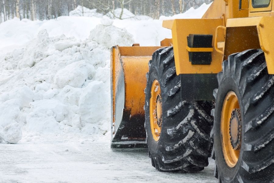 Image depicts a snow removal truck clearing snow from a parking lot.