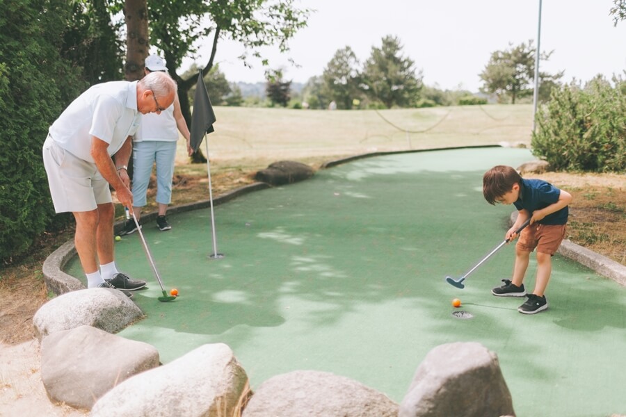 Grandfather and his grandson playing mini golf